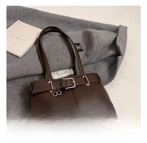 Close-up of a vintage dark brown leather underarm bag with a stylish silver metal buckle