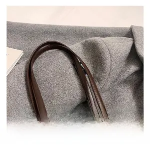 Close-up of thick brown leather handle with silver metal buckle on a chic baguette bag