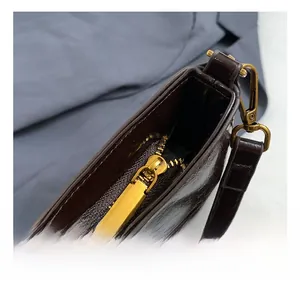 Macro detail of dark brown patent leather bag with vintage gold zipper and hardware hooks