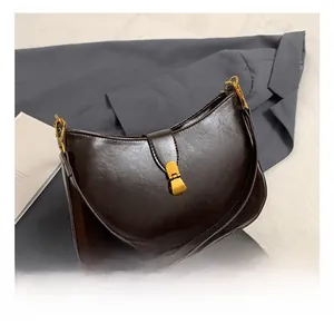 Close-up of a dark brown half-moon shoulder bag with glossy finish and gold metal buckle