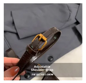 Detail of adjustable dark brown faux leather shoulder strap with gold metal buckle