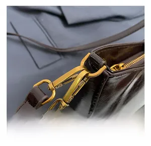 Close-up of vintage gold lobster clasp and glossy dark brown leather strap detailing