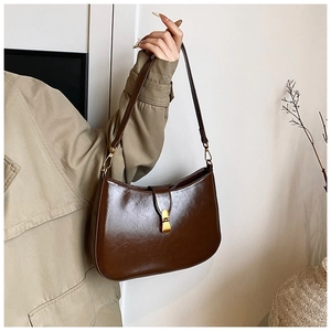 Detail view of a vintage dark brown leather hobo bag held by a model in a trench coat