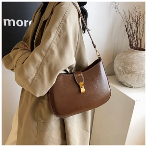 Detailed view of deep brown vintage half-moon bag with gold metal buckle on a shoulder