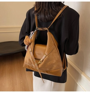 Detail of dark brown tote backpack with embossed leather logo and cute plush bear charm