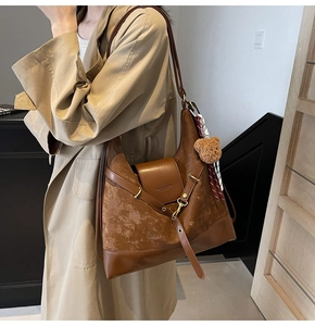 Detail of brown matte tote bag with teddy bear charm and striped scarf on model