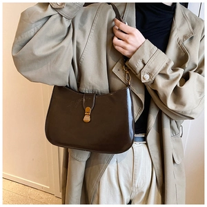 Detail of dark brown glossy leather crescent bag with elegant gold metal clasp hardware