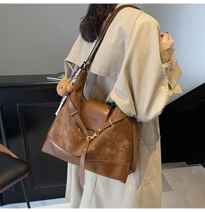 Close-up of large brown tote bag with suede stitching details and bear pendant