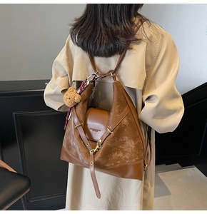 Close-up of brown tote bag with matte texture stitching and a plush bear charm