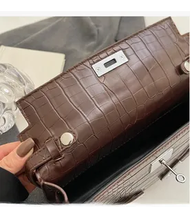 Macro view of dark brown crocodile texture leather bag with silver metal swivel lock detail
