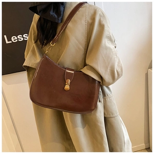 Detail of dark brown vintage faux leather shoulder bag with golden metal clasp on model