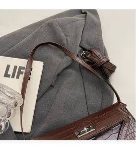 Detailed view of dark brown crocodile embossed leather bag with silver twist lock closure