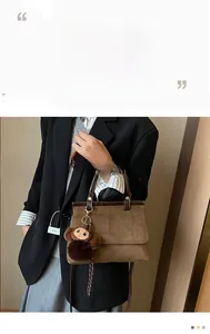Détail du sac à main marron mat avec boucles en laiton et pendentif singe en peluche