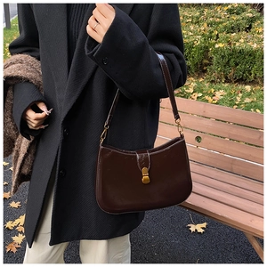 Detail of vintage dark brown faux leather hobo bag with a gold buckle in autumn setting