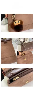 Détails d'un sac à main en daim marron avec surpiqûres et pendentif en peluche doux