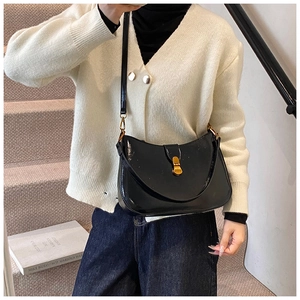 Detail of black glossy crescent crossbody bag with a polished gold metallic buckle