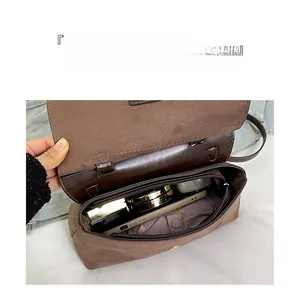 Détail du grand sac bandoulière en daim marron montrant le rangement intérieur organisé