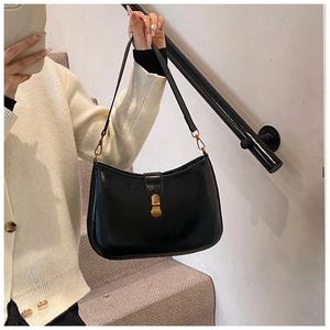 Detail of vintage gold buckle on a black glossy crossbody shoulder bag with sleek finish