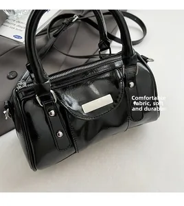 Detail of black glossy cylindrical bag with silver hardware and soft fabric texture