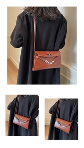 Detail showing brown crocodile pattern leather texture and silver buckle on the shoulder bag