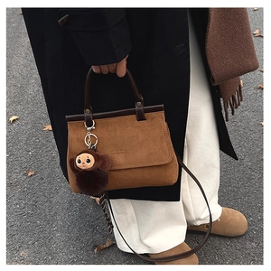 Détail du sac cabas vintage en daim marron avec charm singe en peluche et bandoulière