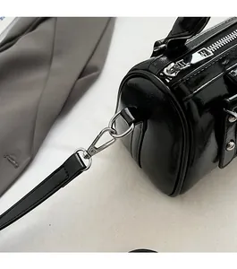 Detail of glossy black barrel bag with silver zipper and detachable metal swivel hook hardware