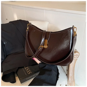 Detail of vintage dark brown leather crescent bag with retro gold metal buckle and hardware