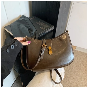 Close-up of retro dark brown leather crossbody bag with gold buckle and adjustable strap