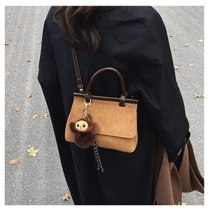 Sac bandoulière en cuir givré marron avec breloque singe sur fond de rue hivernale