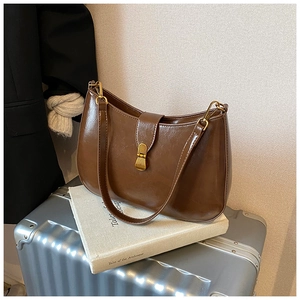 Detail of vintage dark brown glossy leather hobo bag with a gold twist lock on top