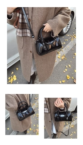 Detail of glossy black patent leather Boston bag with silver buckle in autumn setting