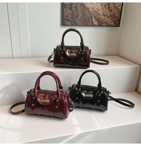 Detailed display of three shiny cylindrical bags in dark brown, wine red, and black colors