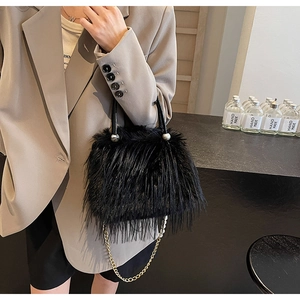 Detail of black faux fur bucket bag with pearl strap and golden chain on beige blazer