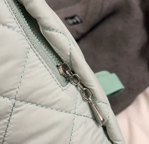 Détail de la fermeture éclair argentée sur le sac à dos matelassé vert menthe élégant