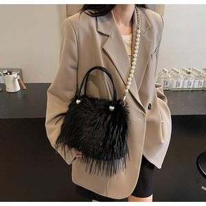 Detail of black faux fur bucket bag featuring elegant pearl handle and crossbody strap