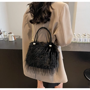 Close-up of black faux fur bucket bag featuring luxury pearl handle and gold chain strap