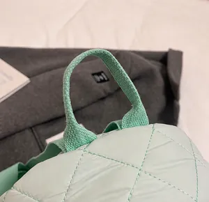 Gros plan des poignées rembourrées et des coutures matelassées du sac fourre-tout vert clair