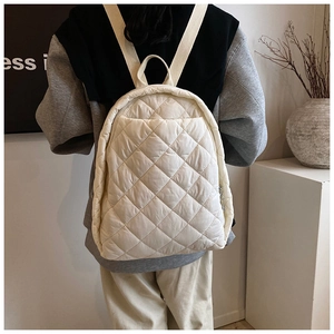 Sac à dos matelassé beige montrant les surpiqûres en losange et les bretelles au dos