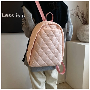 Détail d'un sac à dos rose matelassé avec motif losange et bretelles tissées