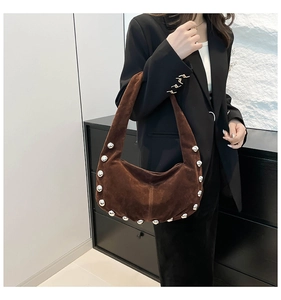 Detail of dark brown suede hobo bag with silver rivet trim on a model shoulder