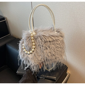 Detail of light gray faux fur bucket bag featuring pearl beads and gold chain strap