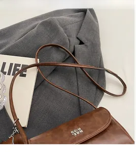 Vue rapprochée du sac bandoulière en cuir marron avec détails métalliques et lanière