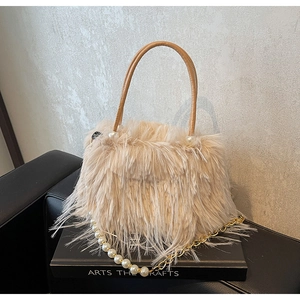 Detail of beige faux fur handbag featuring pearl shoulder strap and leather handle