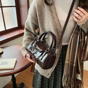 Minimalist dark brown cylinder shoulder bag with glossy finish and retro handle style