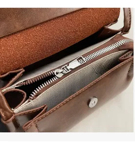 Détail du sac vintage marron avec fermeture éclair argentée et doublure à chevrons