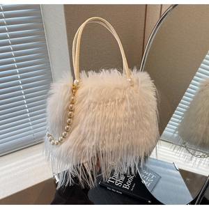 Close-up of white plush bucket bag with elegant pearl chain handle and soft faux fur texture