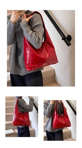 Close-up of red glossy hobo bag with drawstring detail shown in a lifestyle setting