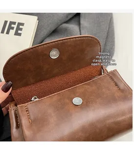 Gros plan du sac bandoulière vintage marron avec fermeture magnétique et texture grainée