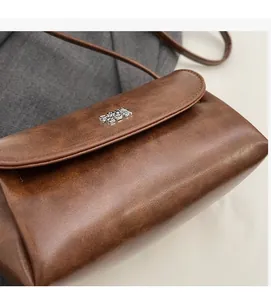 Gros plan du sac à bandoulière rétro en similicuir marron avec rabat et boucle argentée
