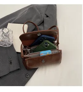 Vue intérieure du sac en cuir marron montrant les compartiments et la poche zippée
